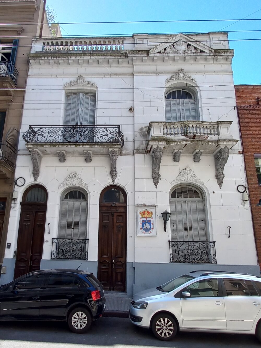 Fachada italianizante de Piedras 848: dos plantas, balcones de hierro forjado, molduras y el azulejo con el escudo de Oleiros junto a la puerta.